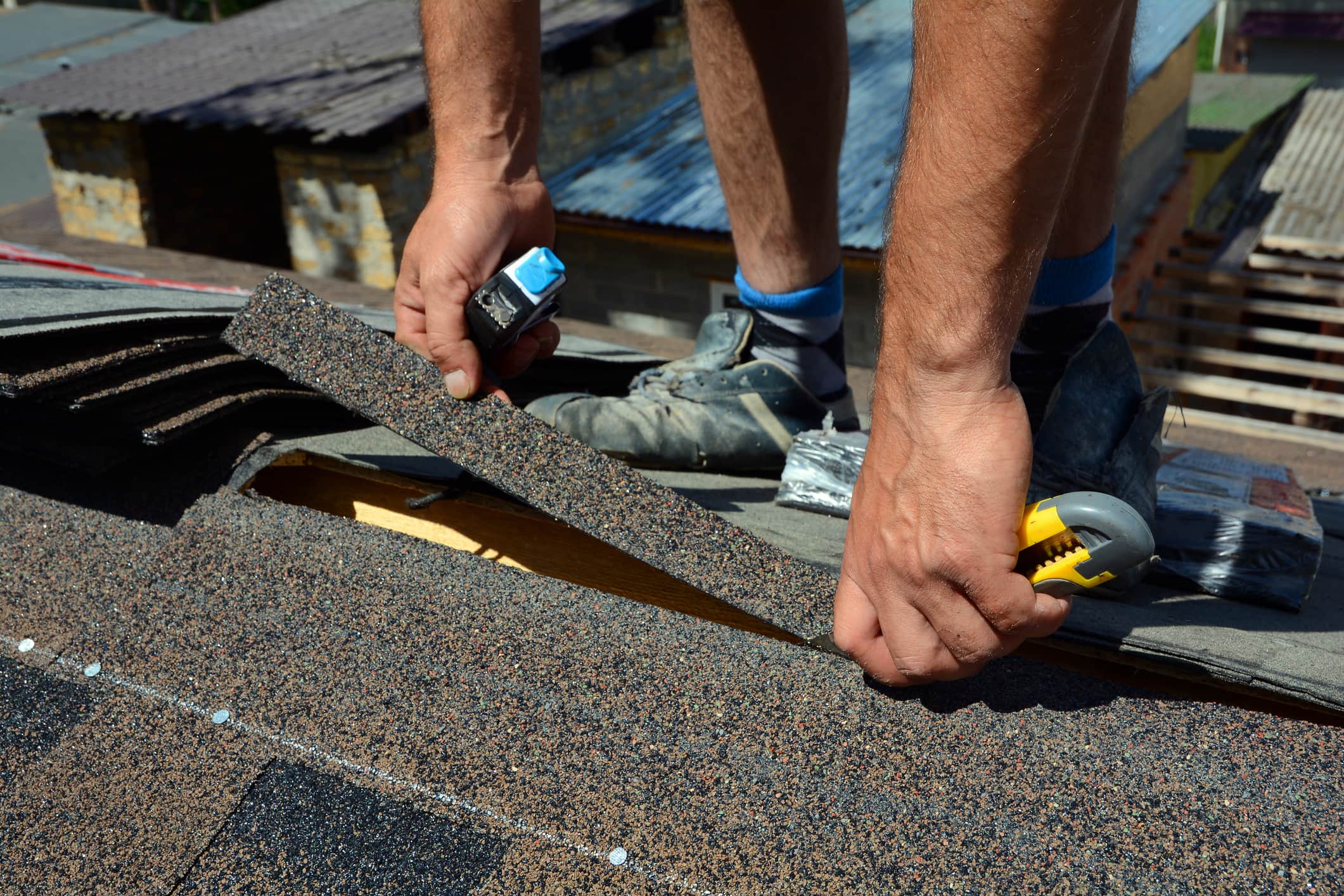 Repairing of roof by cutting felt or bitumen shingles during waterproofing works.